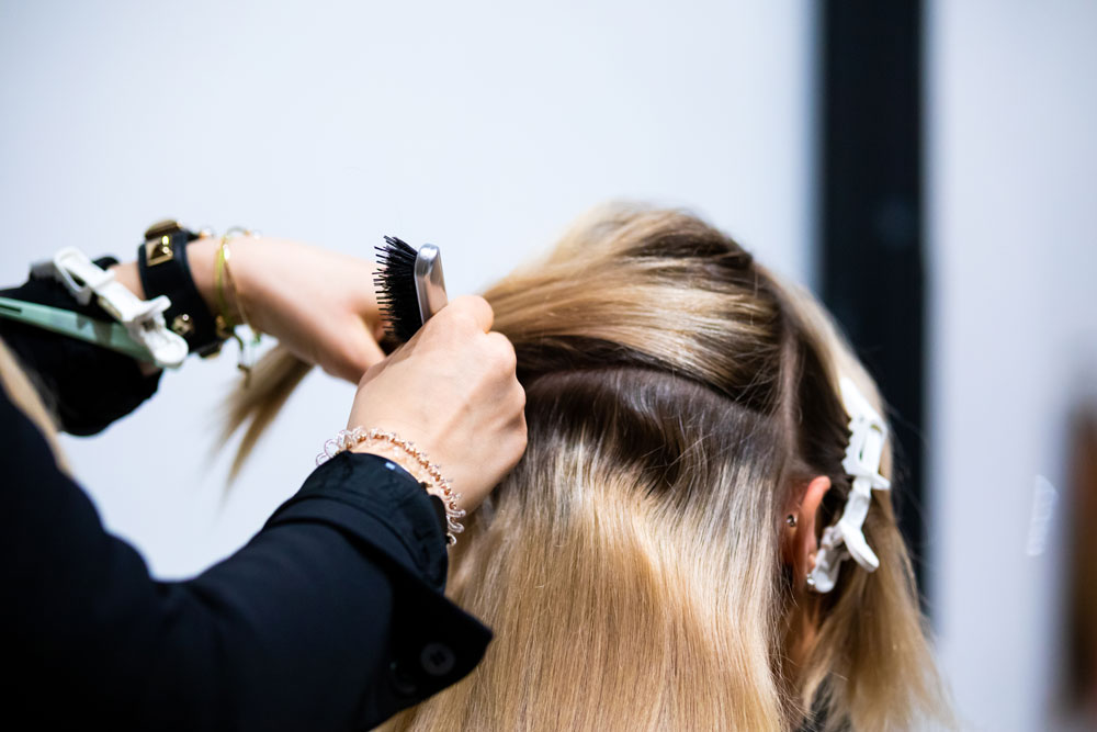 Friseurin bereitet Haar für Tape-in-Extensions vor
