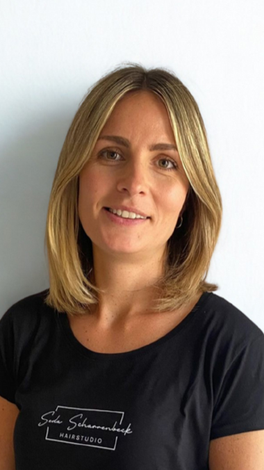 Porträt von Sabrina Lischka, Friseurin mit mittellangen blonden Haaren und schwarzem T-Shirt
